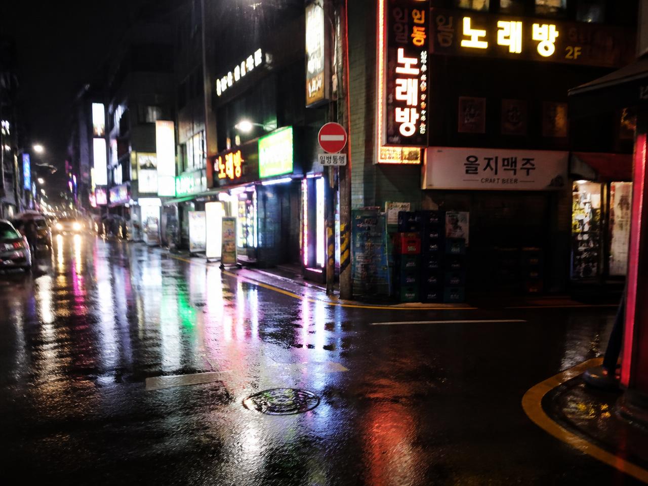 Rainy Seoul street at night lit by neon signs
